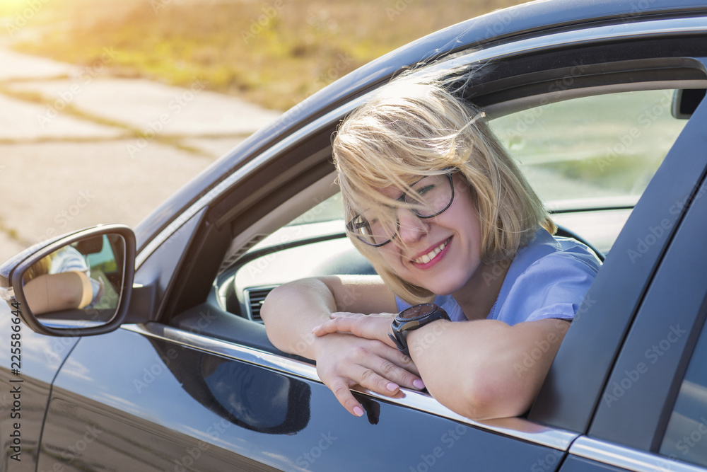 Blonde Woman sitting in car and smiling . Blonde Woman sitting in car and smiling .