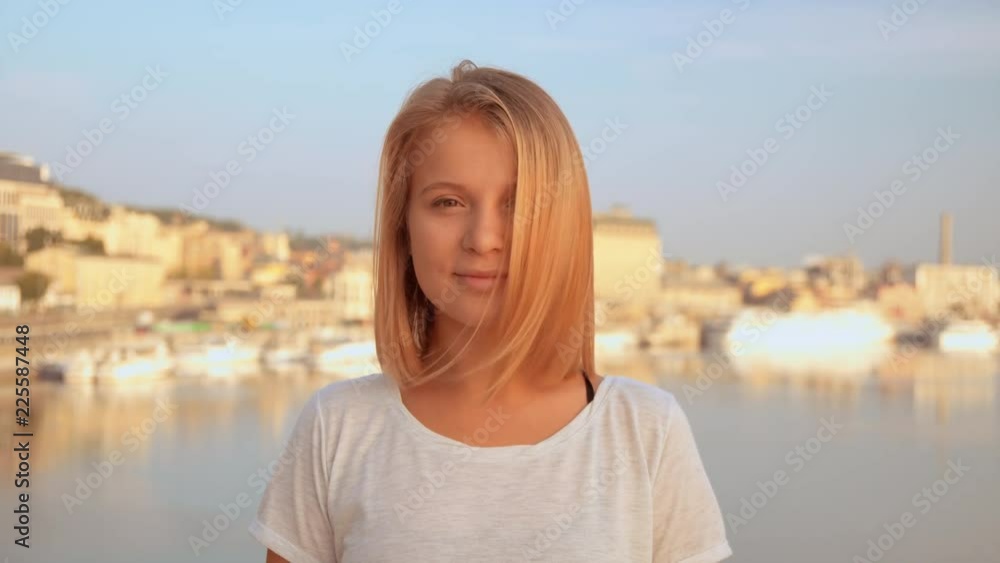 lady is wearing white t-shirt. female standing with seaside at the background. lady is wearing white t-shirt. female standing with seaside at the background.