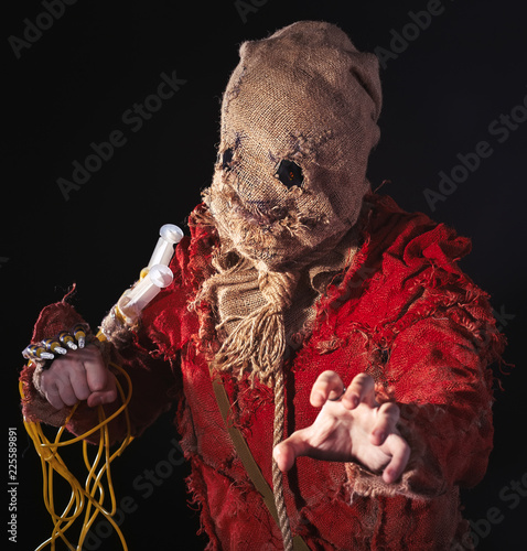 Tablou pe pânză Scary Scarecrow character in a sackcloth suit with syringes on dark background