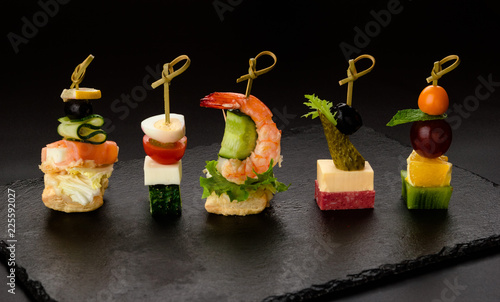 Different kind of snaks, small canape with cherry tomatoes, cheese, sausages, vegetables and fruits on skewers