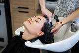 Beautiful brunette washes hair in a beauty salon