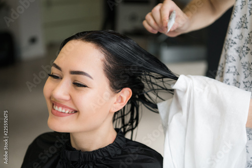 Hairdresser cutting woman's hair in salon, smiling, front view, close-up, portrait © romankosolapov