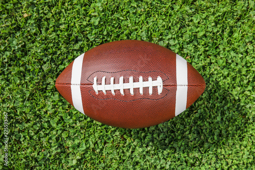 Ball for American football on fresh green field grass, top view