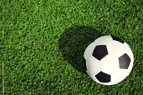 Soccer ball on fresh green football field grass  top view. Space for text