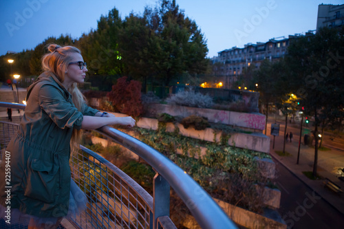 Beautiful girl looks into the distance in the lights of the evening Paris