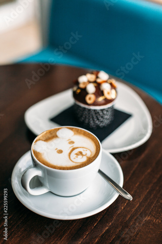 Cup of hot bear latte art coffee with delicious cupcake