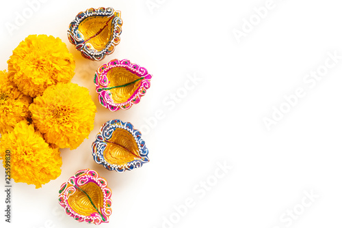 Happy Diwali - Clay Diya lamps lit during Dipavali, Hindu festival of lights celebration. Colorful traditional oil lamp diya with yellow flower on white background photo