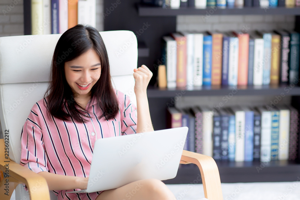 Beautiful of portrait asian young woman excited and glad of success with laptop on chair, girl working living room at home, career freelance business concept. Beautiful of portrait asian young woman excited and glad of success with laptop on chair, girl working living room at home, career freelance business concept.