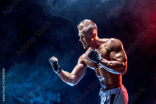 Studio portrait of fighting muscular man in smoke on dark background © zamuruev