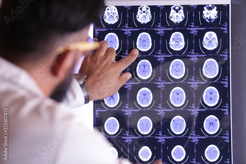 doctor looking at an xray tomography images, Tomography is imaging by sections or sectioning, through the use of any kind of penetrating wave. The method is used in radiology.