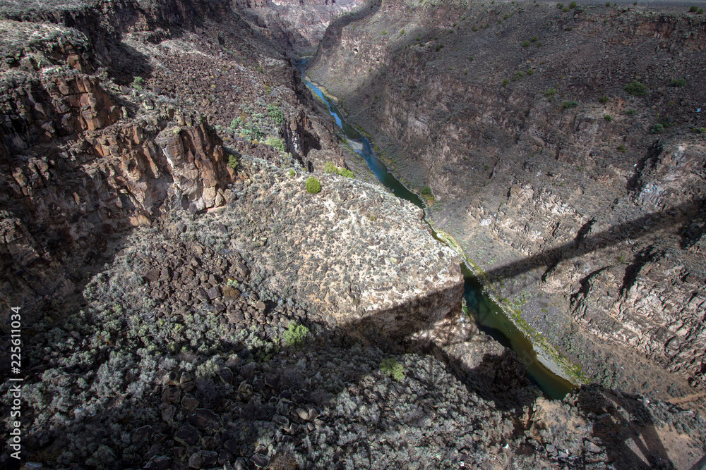 Obraz premium The bridge over the Rio Grande Gorge casts a long shadow across its 800' deep canyon, which lies on the Taos Plateau in New Mexico; view looking north from US Hwy 64