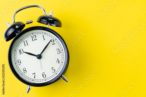 Time, deadline or reminder concept, vintage ringing black alarm clock with white face on yellow background in flat lay or top view, studio shot with copy space