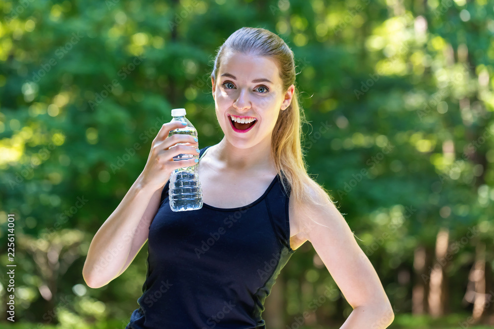 Young woman with a water bottle on a bright summer day in the forest Young woman with a water bottle on a bright summer day in the forest