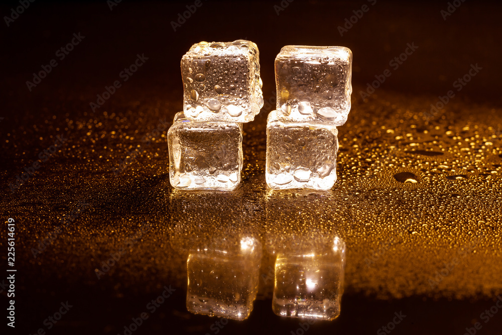 Golden ice cubes reflection on black table. Golden ice cubes reflection on black table.