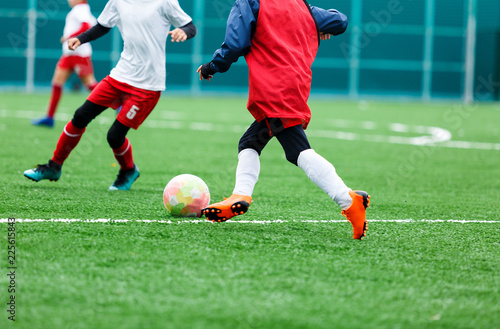  football teams - boys in red, blue, white uniform play soccer on the green field. boys dribbling. dribbling skills. Team game, training, active lifestyle, hobby, sport for kids concept © Natali