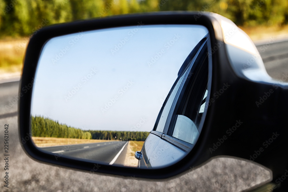 View of the road through the rear view mirror in the car View of the road through the rear view mirror in the car