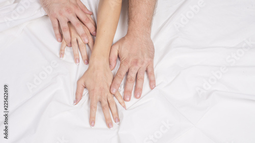 Close up hands of a couple make love hot sex on a bed.