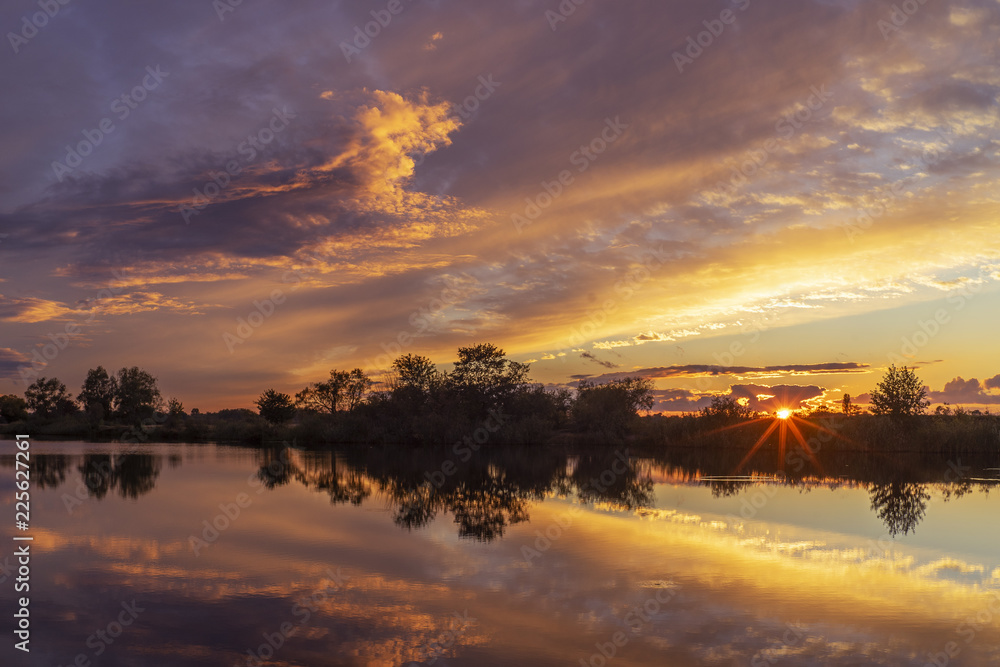 Obraz premium Magical sunset over the river in rural terrain. Natural calm beautiful landscape. The sun's rays.
