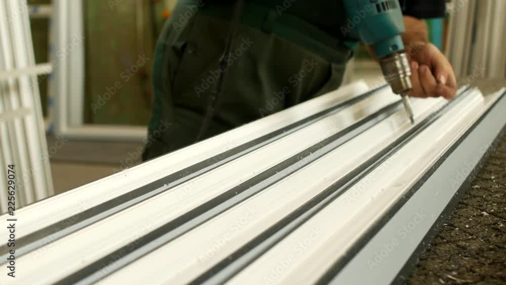Manufacturing windows pvc, male worker twists screws in the profile pvc for window manufacturing, shop and windows, production Manufacturing windows pvc, male worker twists screws in the profile pvc for window manufacturing, shop and windows, production