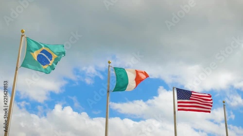 Mulit national flags flapping in the air against a blue clouded sky photo