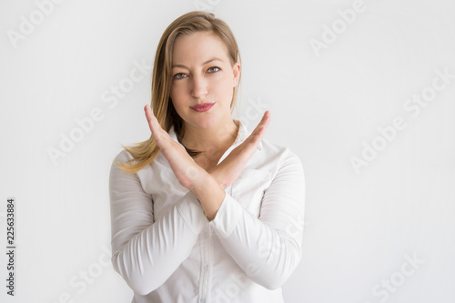 Serious beautiful woman showing crossed hands and looking at camera. Lady denying something. Prohibition concept. Isolated front view on white background.