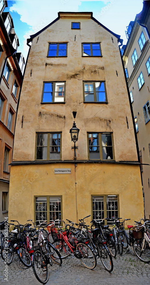 vertical panorama of old narrow city street with parked bicycles on it. Stockholm, Sweden