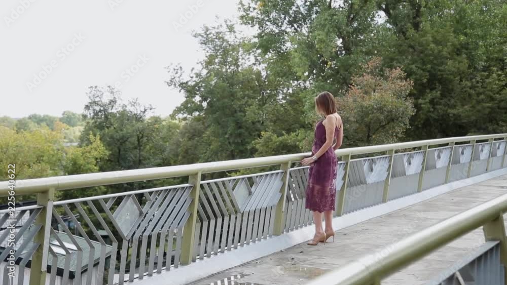 A very beautiful and sexy girl is standing on the bridge and looking to the distance. A very beautiful and sexy girl is standing on the bridge and looking to the distance.