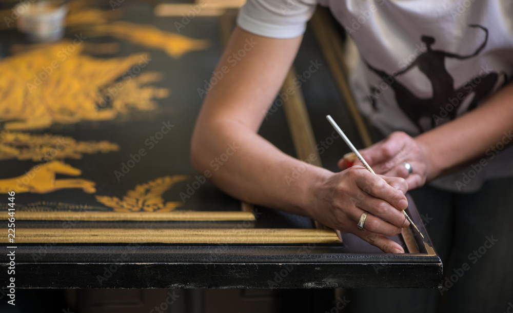 Obraz premium painter decorator draws pattern with a thin brush