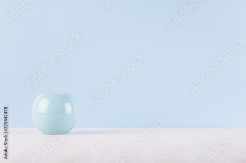 Elegant modern home decor of smooth ceramic circle vase on white wood table and light blue wall.