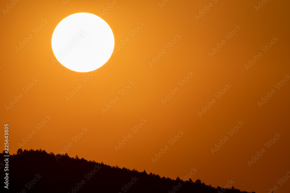 Big sun circle at dusk over mountain with orange sky Big sun circle at dusk over mountain with orange sky