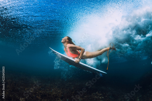 Attractive surfer woman dive underwater with under wave.
