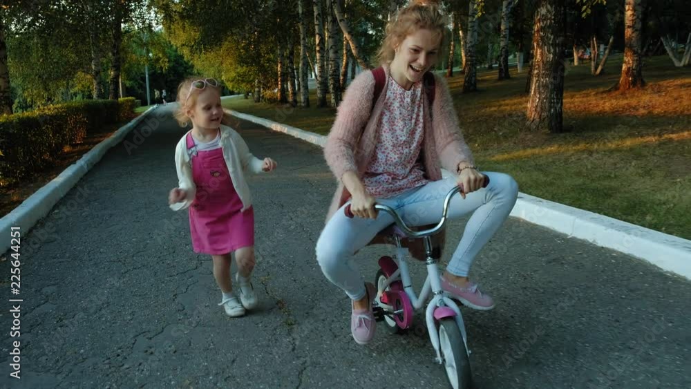 custom made wallpaper toronto digitalA happy, beautiful, little girl with long blond hair in a pink skirt and jumper rides a children's bike on the road, she smiles.