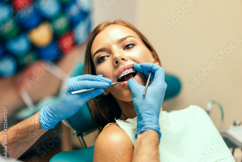 Dentist examine female patient with braces in denal office. photo