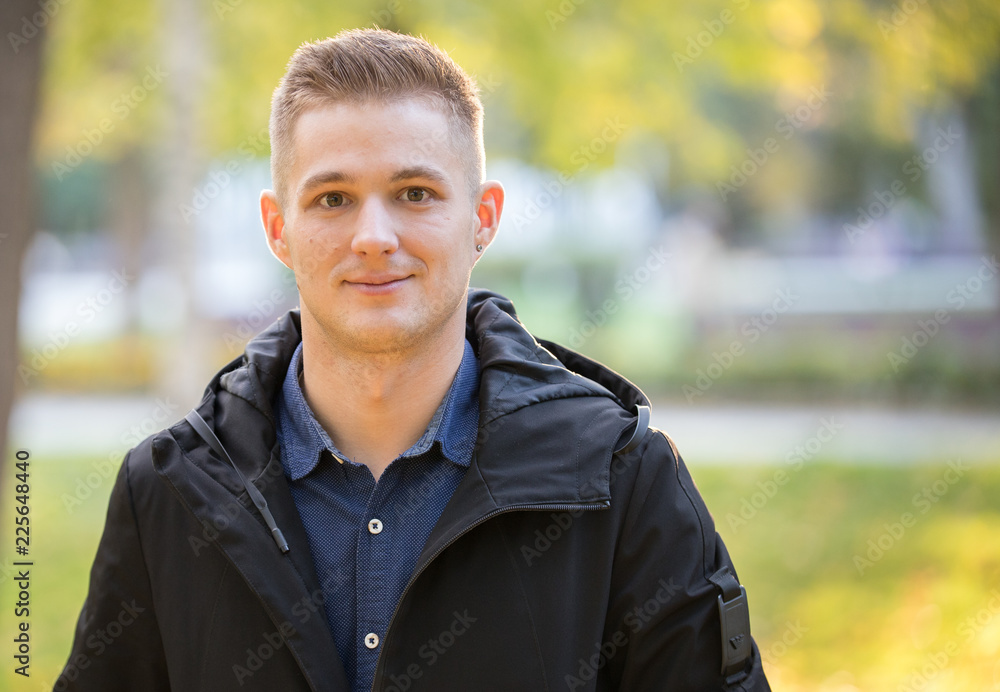 Handsome and young man in a black jacket standing in the park. Portrait Handsome and young man in a black jacket standing in the park. Portrait