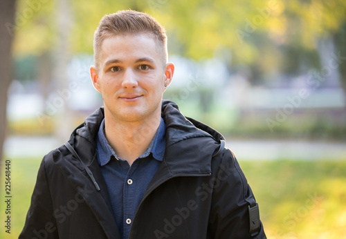 Handsome and young man in a black jacket standing in the park. Portrait © KONSTANTIN SHISHKIN