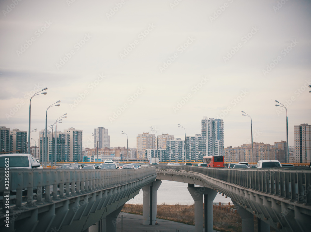 Obraz premium Cars go on bridge-roads on the background of the daytime overcast city
