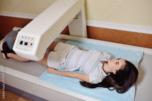 Konstfotografi young pretty girl on examination in a modern clinic by densitometry - checking the density of bone tissue