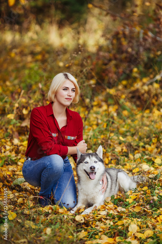 Beautiful caucasian girl plays with husky dog in autumn forest