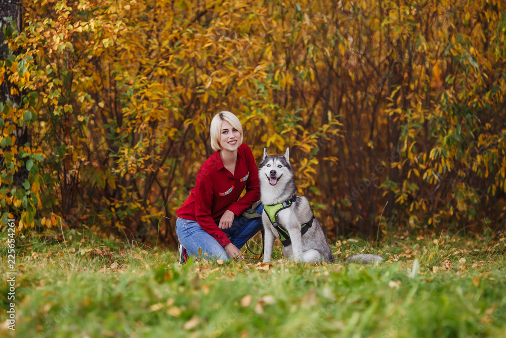 Beautiful caucasian girl plays with husky dog in autumn forest