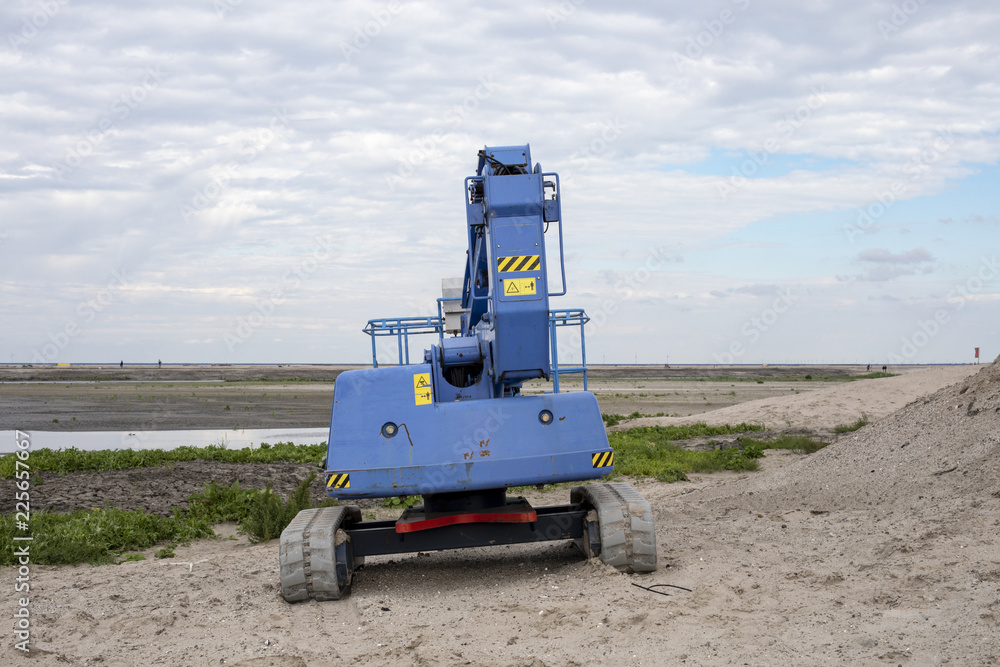 Obraz premium A blue tractor at the marker wadden, an artificial archipelago in the Markermeer, a lake in the Netherlands, wetlands made, with blue cloudy sky.