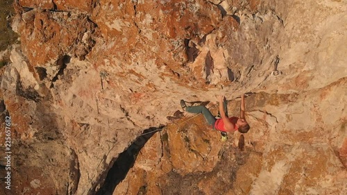Aerial shot of young brave woman climber climbs the rock breaks, falls down and hangs on a safety rope. Slow motion.