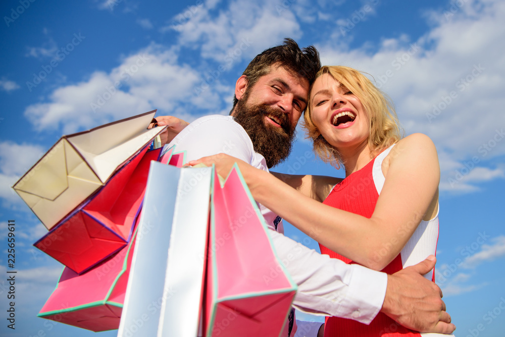 Shopping brings positive emotions. Man beard and blonde girl enjoy buy clothing. Family bought excellent clothes. Happy couple satisfied purchases. Couple with shopping bags hugs blue sky background Shopping brings positive emotions. Man beard and blonde girl enjoy buy clothing. Family bought excellent clothes. Happy couple satisfied purchases. Couple with shopping bags hugs blue sky background