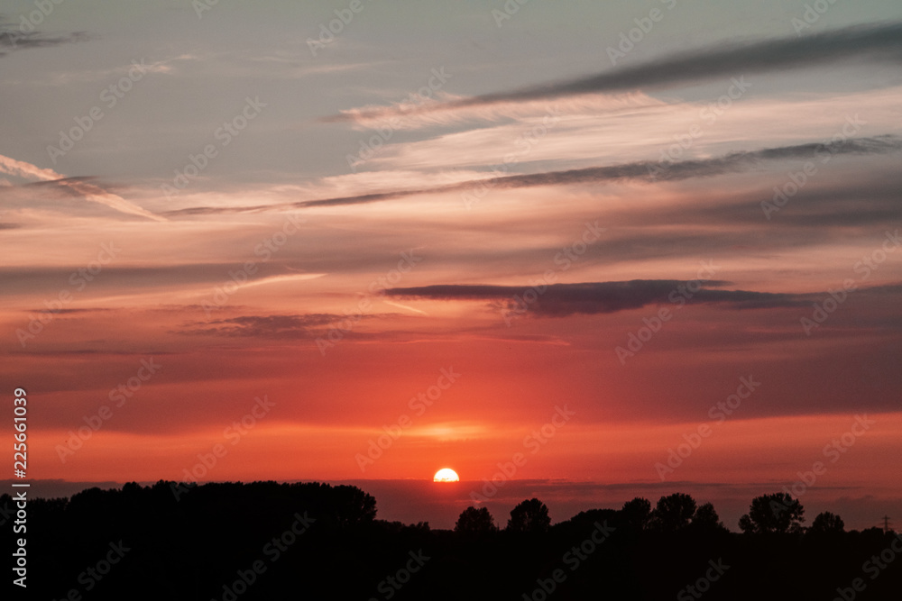 Summer sunset sky with orange bright colors and blue tones. Germany countryside landscape. Brunswick, Lower Saxony in Germany