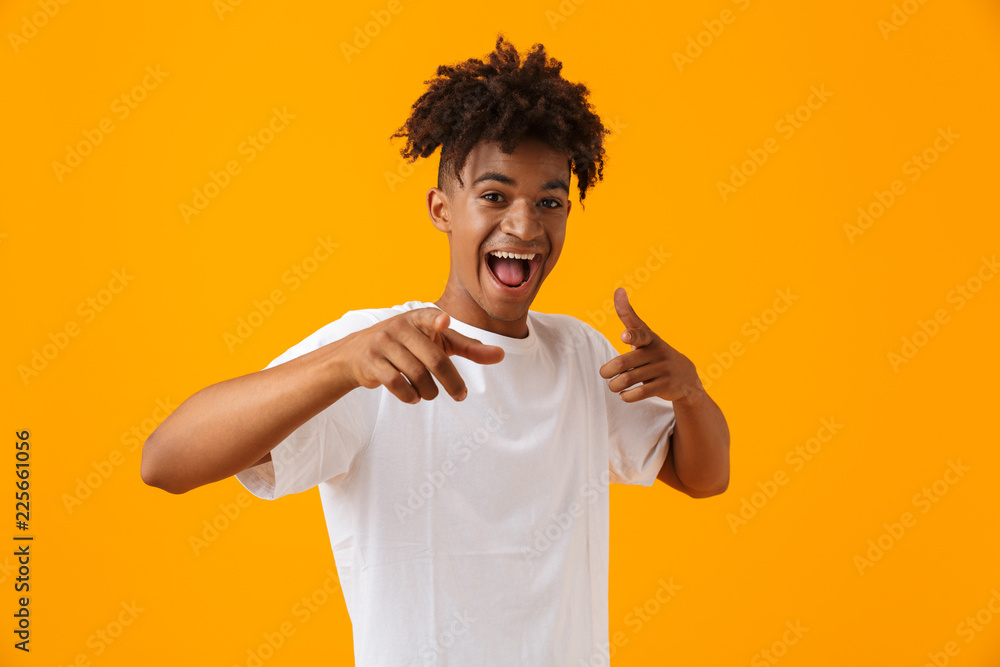 Happy young african man posing isolated over yellow background pointing. Happy young african man posing isolated over yellow background pointing.