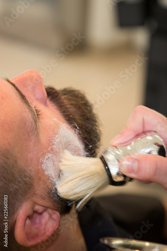young bearded man getting beard haircut at hairdresser at barbershop