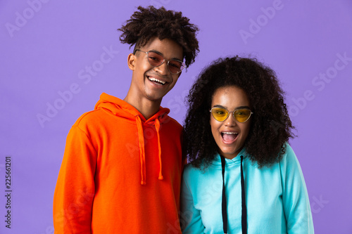 Young cute african couple posing isolated over violet background.