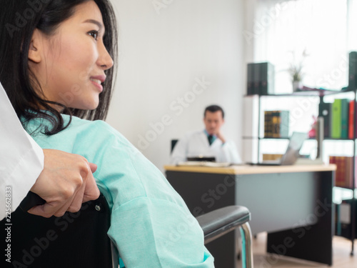 healthcare concept.closeup smiling female patient wheelchair looking outside with blur doctor sitting in clinic.