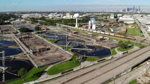 Descending Drone Footage of a Sewage Treatment Plant next to Buffalo Bayou with a Train and the City of Houston Skyline in the Background photo