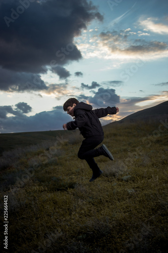 the boy is jumping against the background of the evening horizon