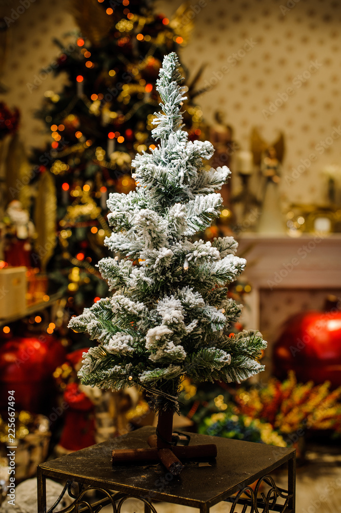 Little artificial Christmas tree on a stand decorated with artificial snow